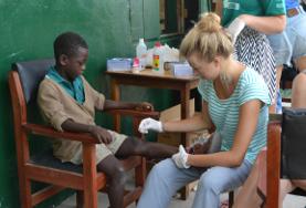 19+ Specials: Freiwilligeneinsätze für junge Erwachsene : Ghana Eine Freiwillige versorgt die Schürfwunde eines jungen Patienten während ihrer Freiwilligenarbeit im Public Health-Projekt in Ghana.