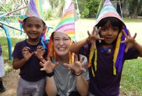 19+ Specials: Freiwilligeneinsätze für junge Erwachsene : Sri Lanka Monsteralarm in Sri Lanka! Mit selbstgebastelten Hüten spielt eine Freiwillige mit zwei Kids im Sozialarbeits - Projekt in Sri Lanka.
