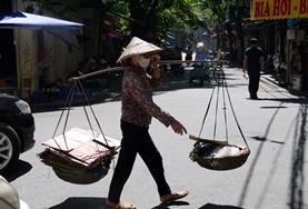 Projekte in Südostasien - Vietnam : Journalismus Eine Frau mit Reis Hut überquert die Straße mit Vorräten für ihren Marktstand.
