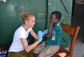 Projekte in Afrika - Ghana : Medizin - Praktikum Eine Freiwillige versorgt die Armwunde eines kleinen Jungens während des Medical Outreach im Medizin - Praktikum.