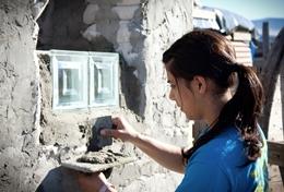 Freiwilligenarbeit in Afrika - Südafrika : Schulferien - Specials - Hausbau Eine Freiwillige verputzt ein neu gesetztes Fenster im Hausbau - Projekt für Schüler/innen im wunderschönen Kapstadt in Südafrika.