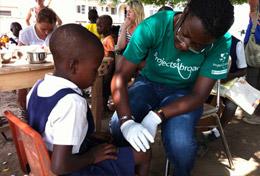 Medizin & Pflege : Ghana Während unserer Gesundheitskampagne auf dem Land in Ghana verarztet eine Schülerin im Schulferien - Special Medizin die Schürfwunde eines Schulkindes.