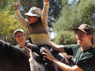 Freiwillige aus dem Pferdetherapie-Projekt helfen bei den Therapiestunden in Bolivien. Ein Junge aus Bolivien nimmt an einer Pferdetherapie-Stunde mit Freiwilligen in Cochabamba teil.