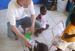 Projekt in der Karibik - Jamaika : Schulferien - Specials - Sozialarbeit Ein Freiwilliger gibt einem kleinen Kind etwas zu Trinken im während seines Freiwilligendienstes in seinen Schulferien auf Jamaika.