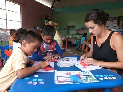 Zwei Kinder basteln mit einer Frewilligen von Projects Abroad zusammen auf den Galapagos – Inseln. Zwei Kinder in Ecuador basteln mit einer Frewilligen zusammen
