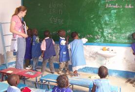 Projekte in Afrika - Senegal : Unterrichten Eine Freiwillige wird im Unterrichts - Projekt im Senegal als Lehrerassistentin tätig und beaufsichtigt Schreibübungen ihrer Schüler/innen an der Tafel.