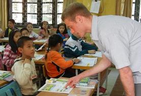 Projekte in Südostasien - Vietnam : Unterrichten Ein Freiwilliger geht im Unterrichts - Projekt in Vietnam verschiedene Vokabeln mit einem Schüler durch.